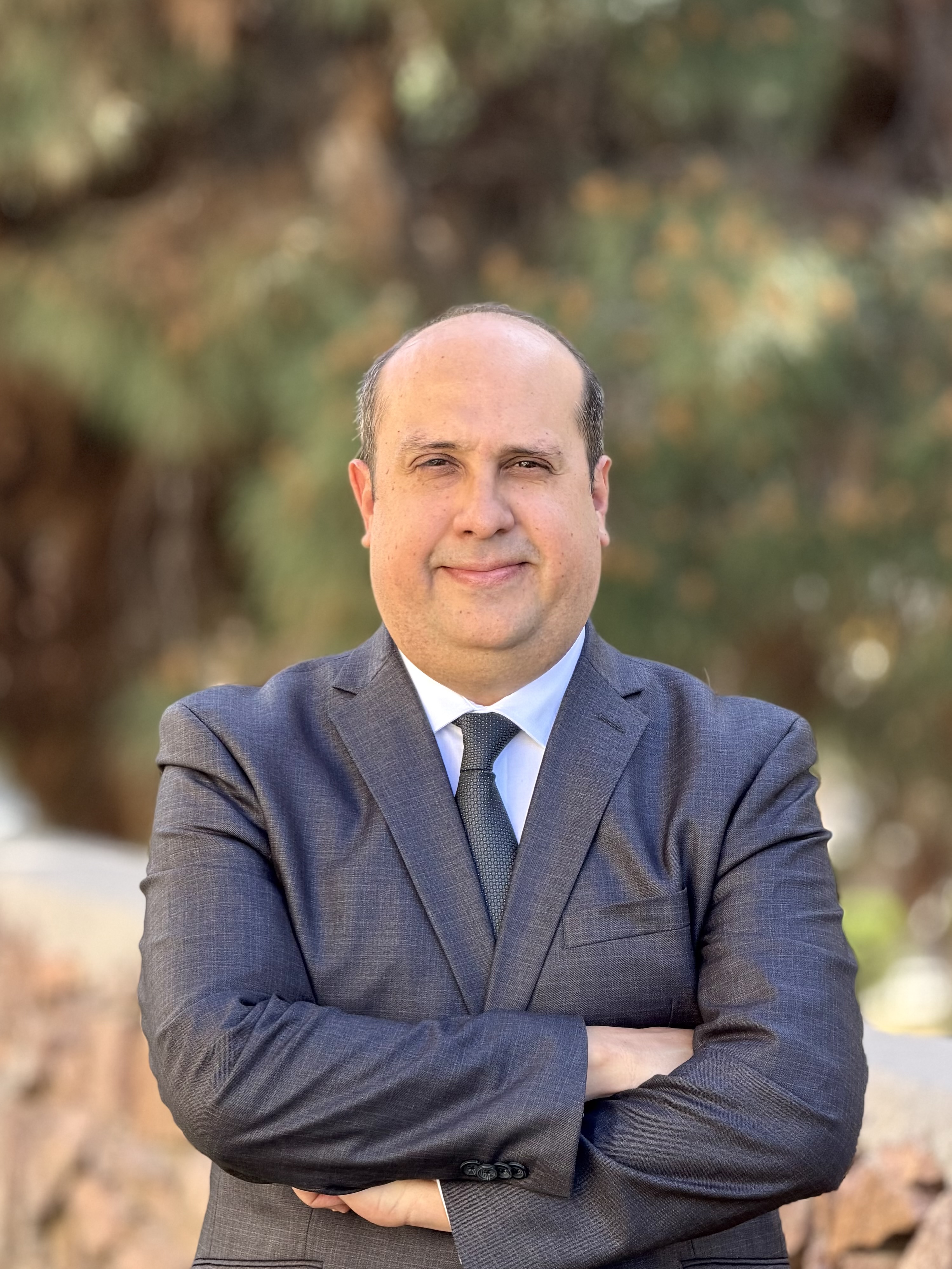 El abogado de inmigración empresarial Luis Gutiérrez Márquez con los brazos cruzados a la luz del día en el exterior. 